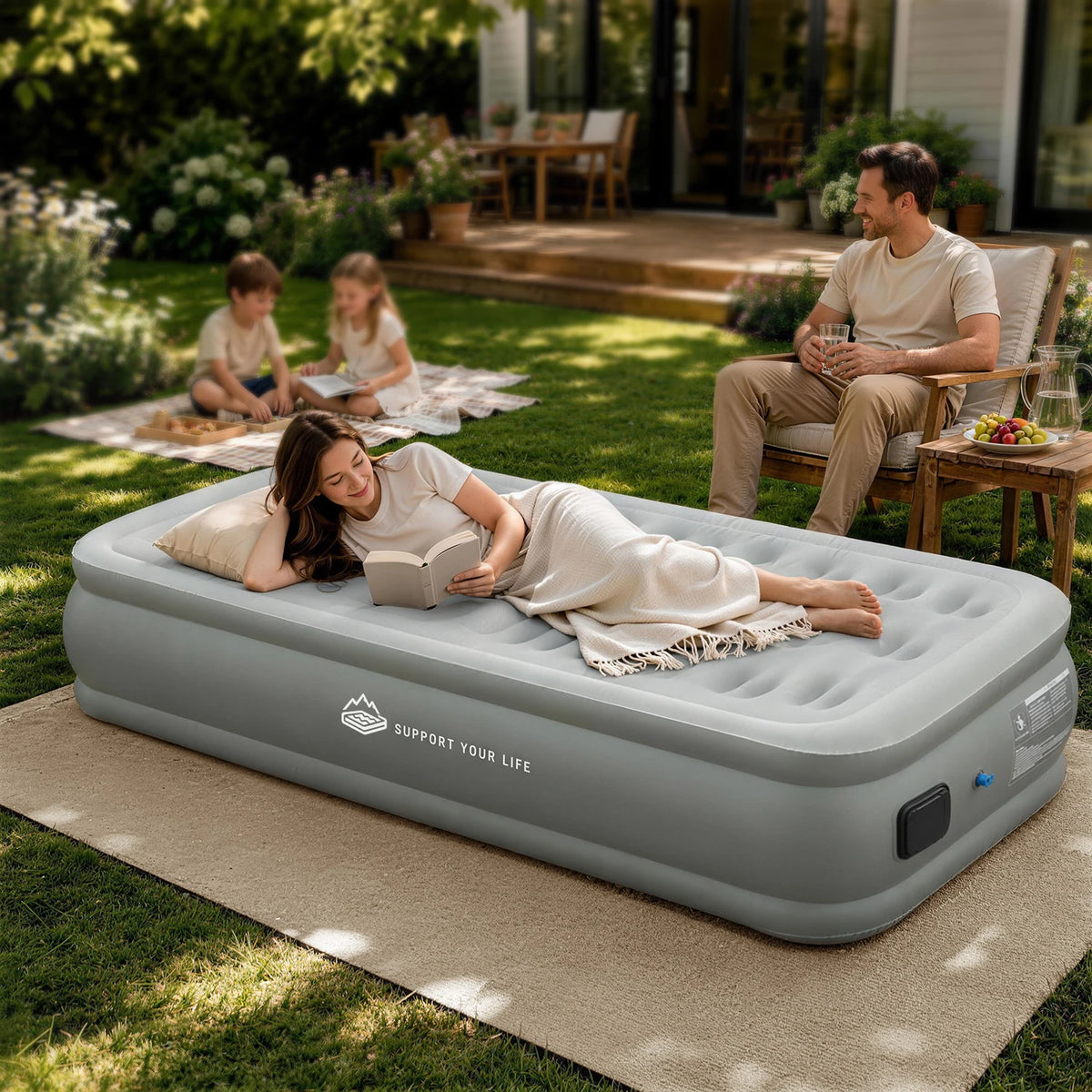 Woman reading on a JUITOY air mattress in a backyard relaxation setup